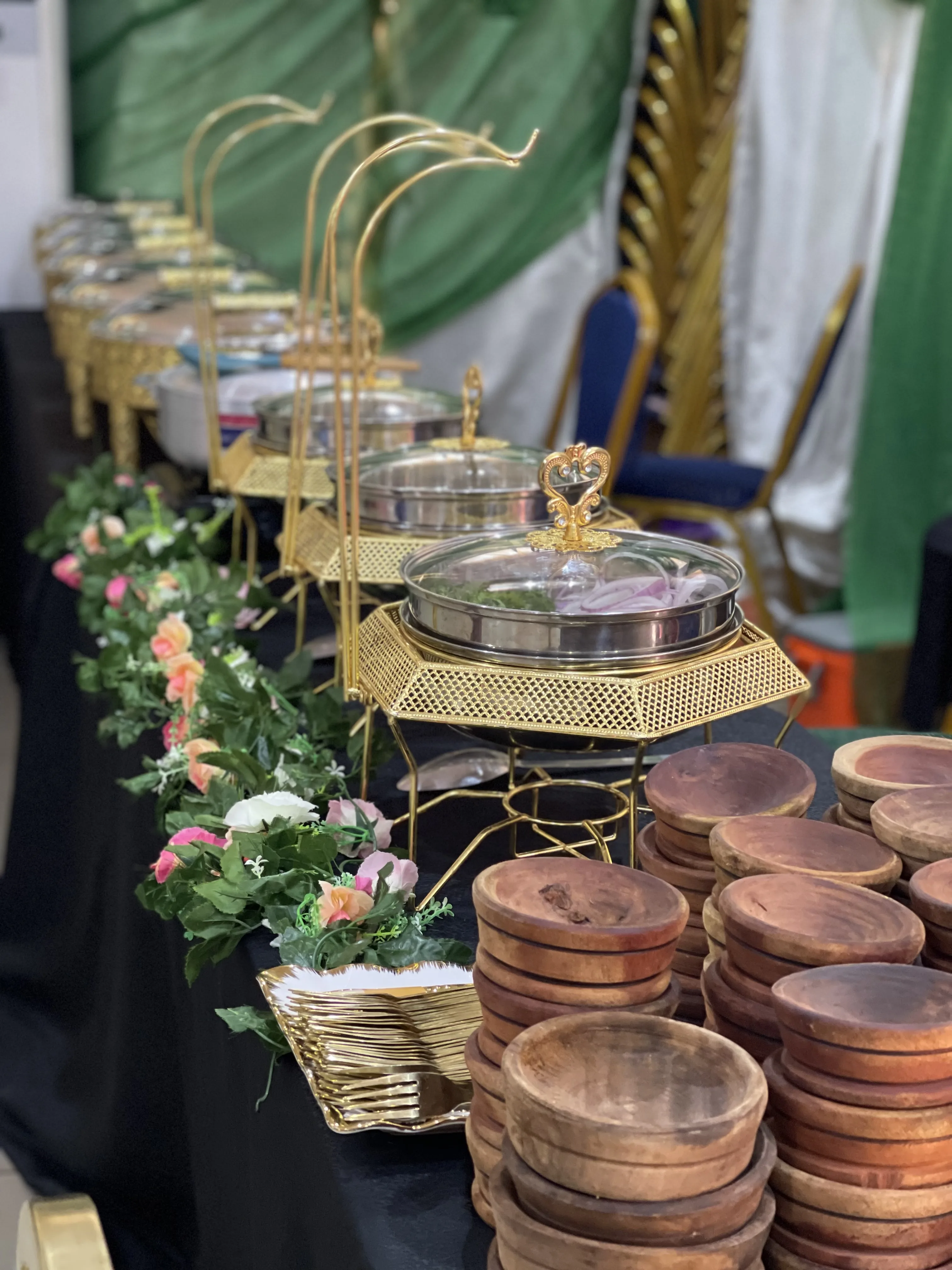 Elegant buffet setup with golden chafing dishes and wooden serving bowls