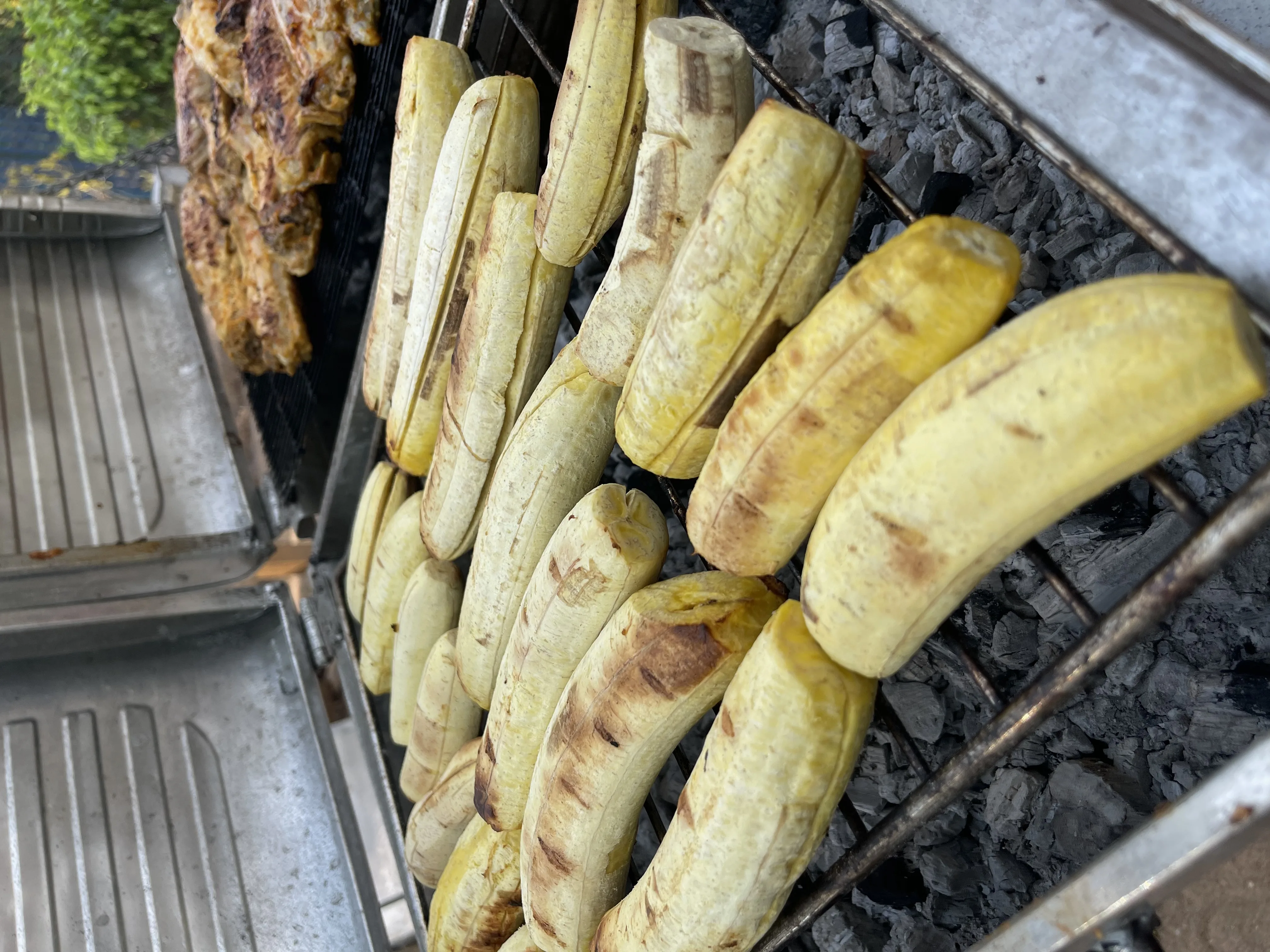 Plantain grilling on charcoal alongside chicken