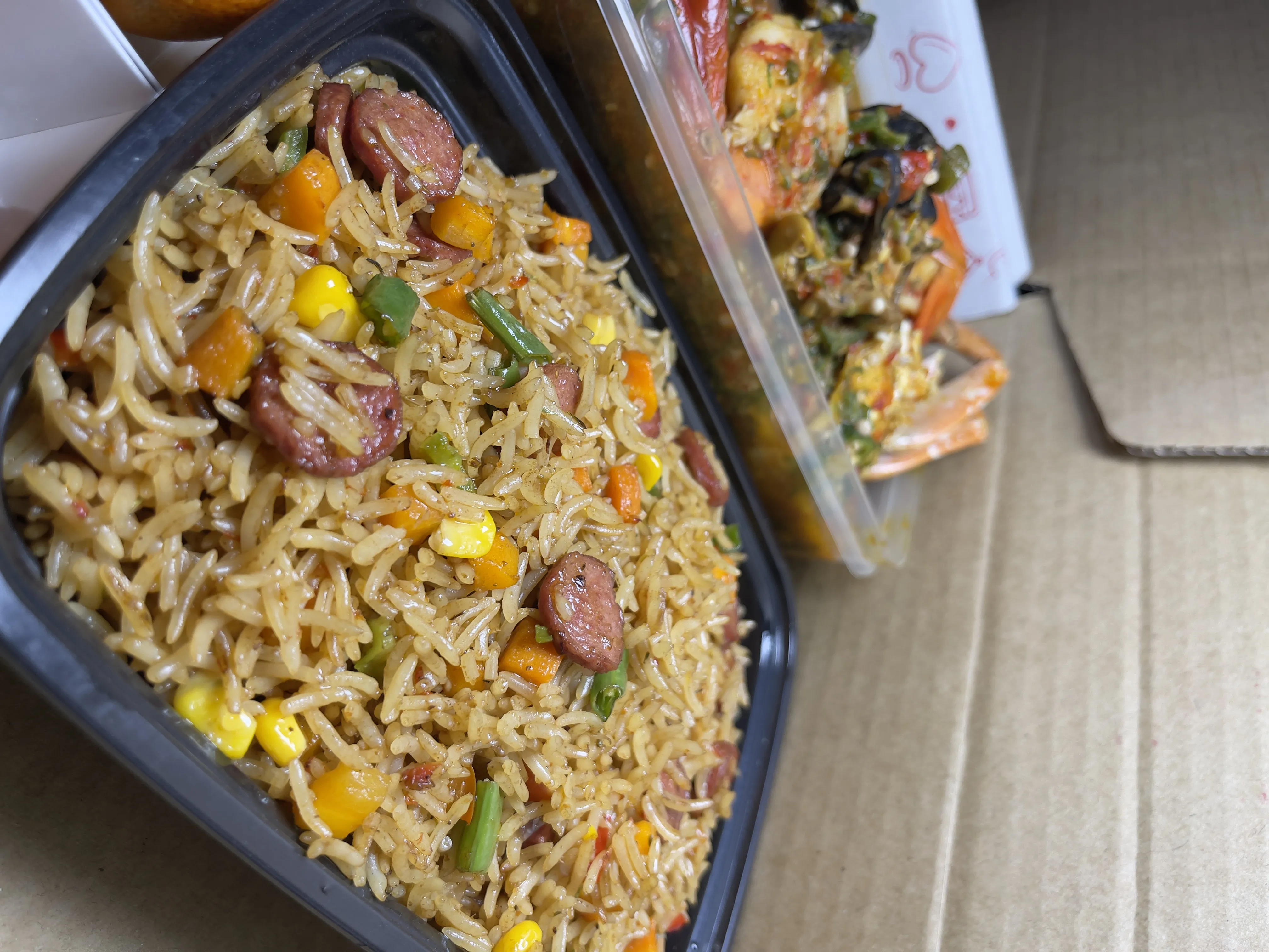 Special fried rice with mixed vegetables and sausage in a delivery tray